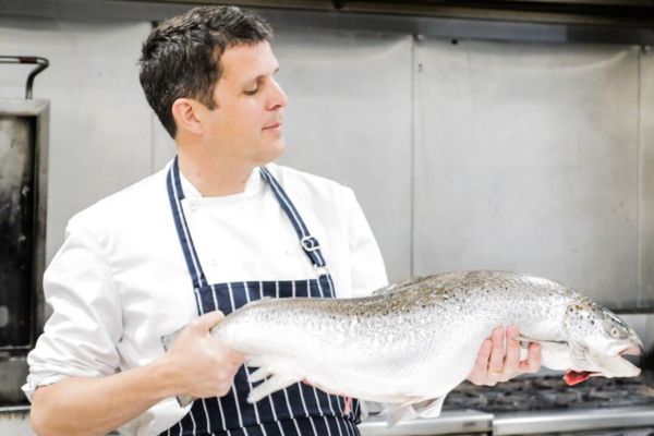 Rob Rees holding a fish in a commercial kitchen